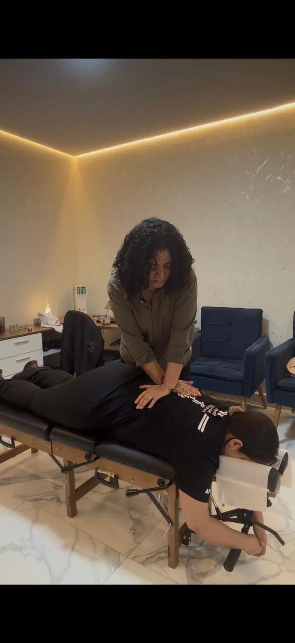 Luciana Lima realizando atendimento de quiropraxia em paciente deitado na maca